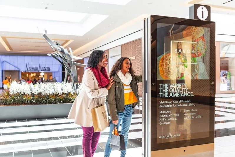 Passants devant un écran publicitaire dans un centre commercial