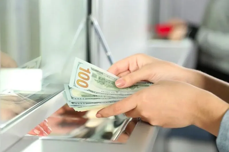 Client comptant des billets de dollar au guichet d’une banque