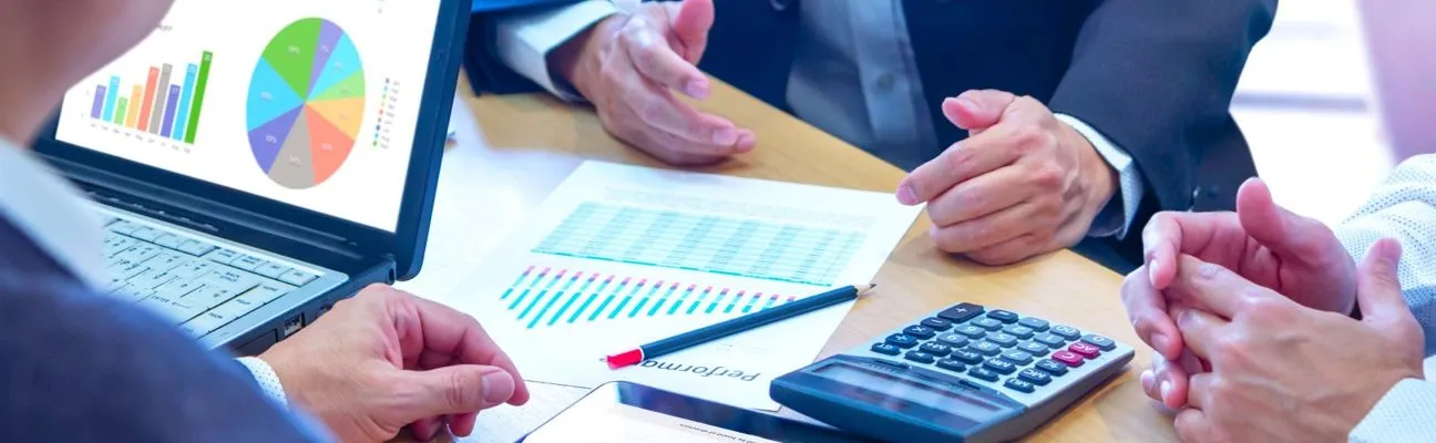 Personnes examinant des graphiques financiers sur un bureau avec une calculatrice