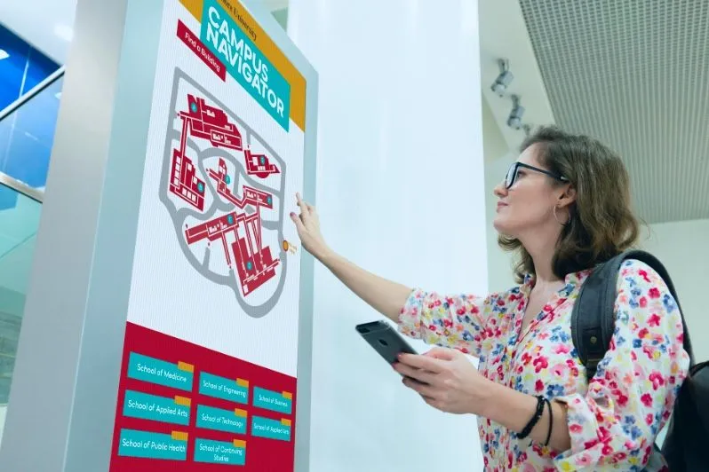 Étudiante utilisant un plan interactif du campus sur un écran tactile