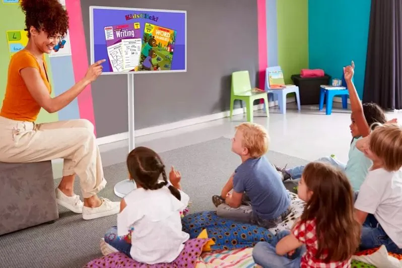 Enseignante et enfants dans une classe avec un écran sur pied