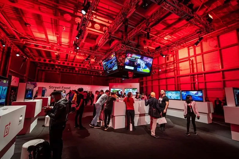 Hall d’une salle de concert éclairé en rouge avec des écrans au-dessus du bar