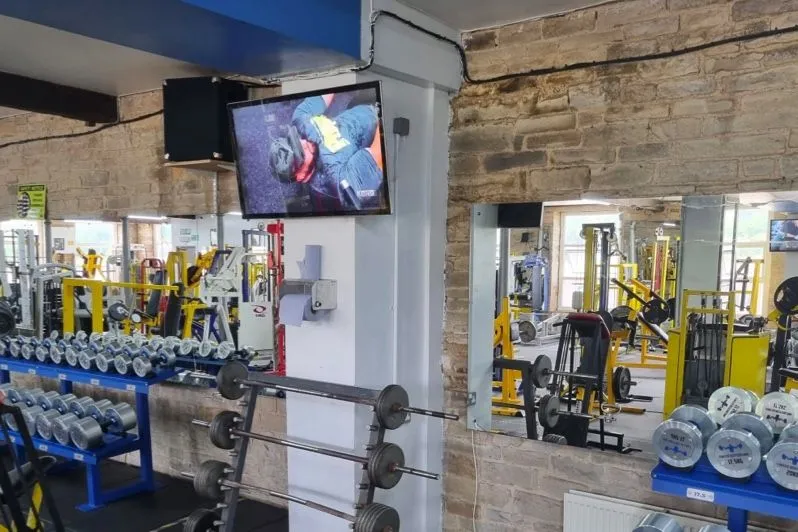Écran diffusant une vidéo d’entraînement au-dessus d’un espace musculation