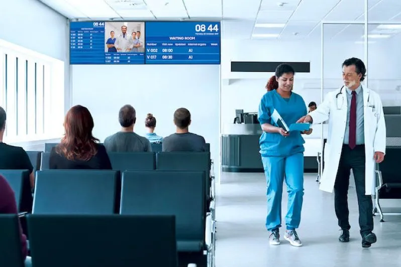 Salle d’attente d’un hôpital avec des écrans au-dessus des sièges