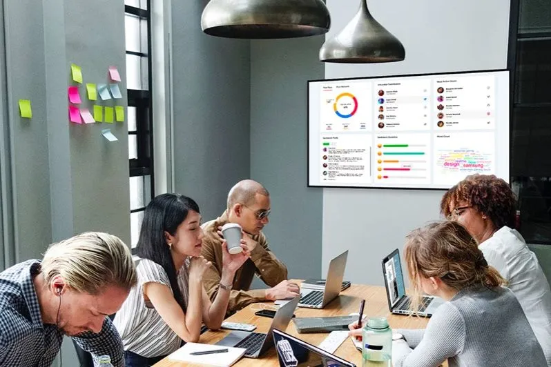 Réunion d’équipe sous un écran affichant des tableaux de bord de l’entreprise