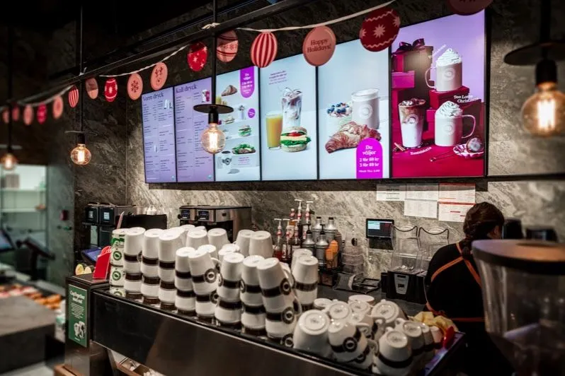 Comptoir d’un café avec une rangée d’écrans de menu