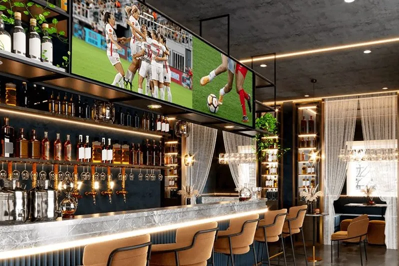 Bar avec des écrans diffusant du sport au-dessus des bouteilles