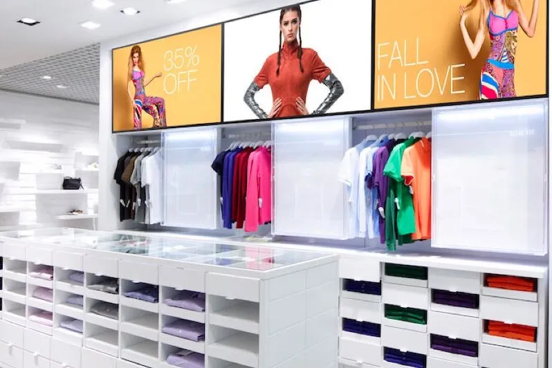 Magasin de mode avec des écrans numériques au-dessus des portants
